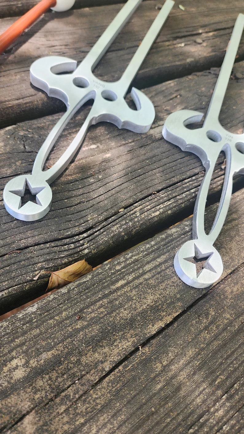 Medical forceps with star-shaped tips on surface beside 128 Hz & 192 Hz Tuning Forks