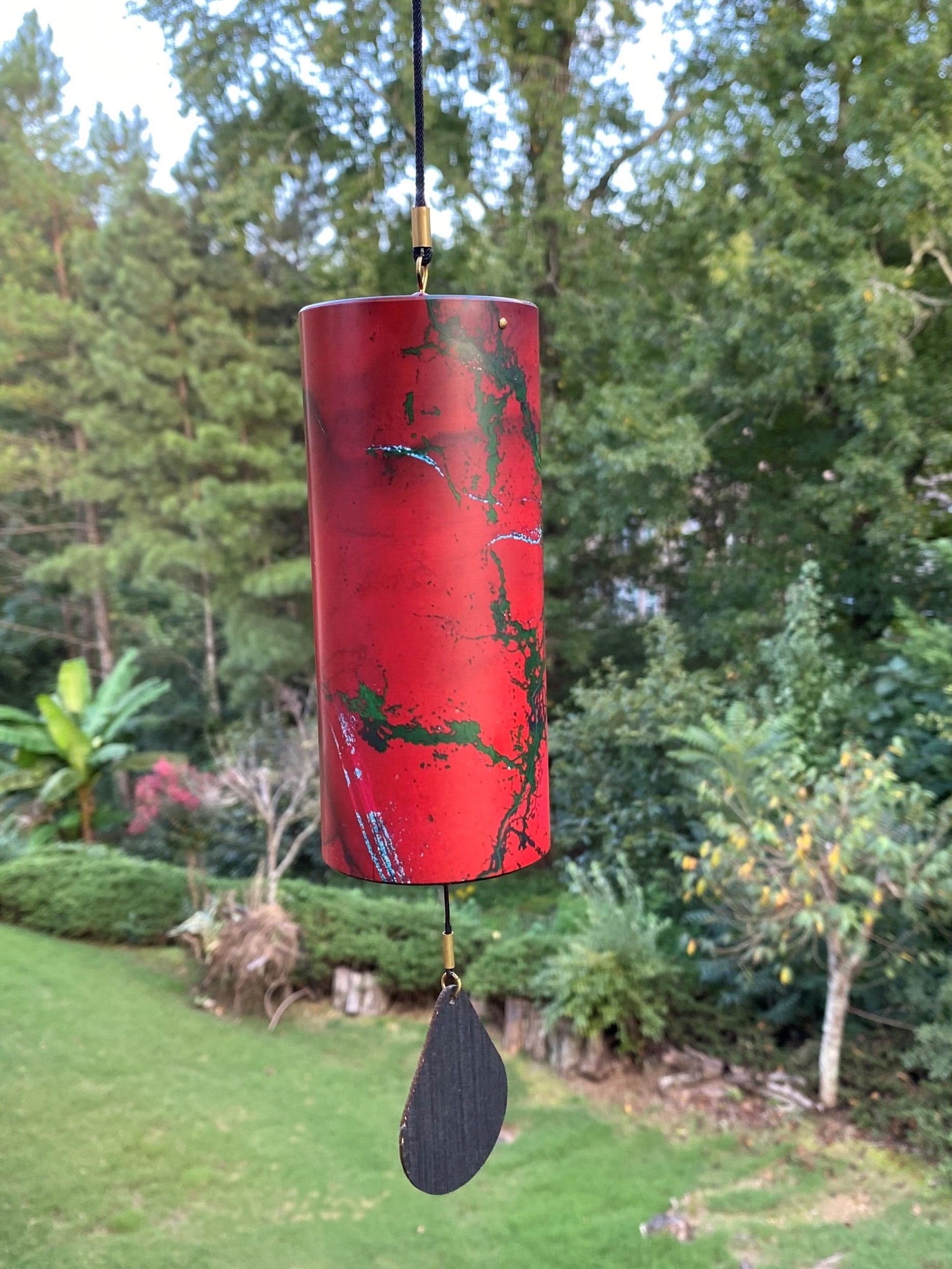 Red cylindrical wind chime with green patterns and black paddle for home and garden