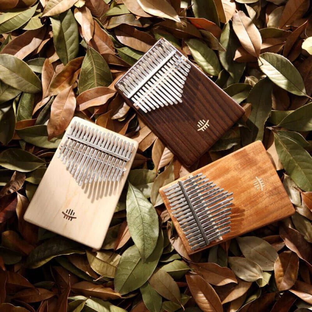 Three Kalimbas with wooden bodies and metal tines, featured in 17 Key Acacia C Tone Flat Board