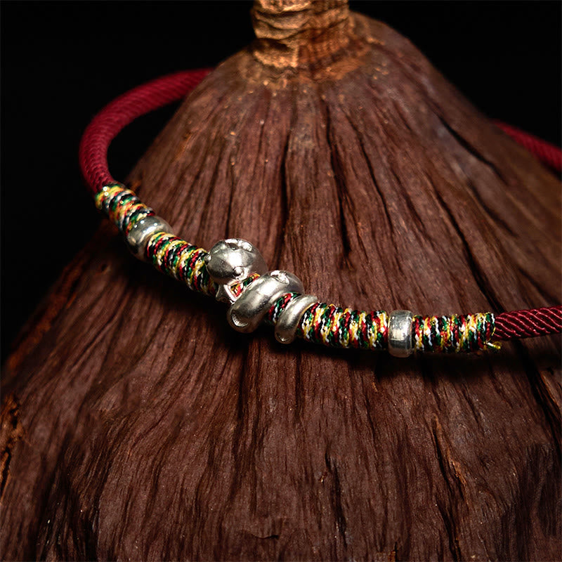 Schutzarmband mit roter Schnur und silberner Schlange