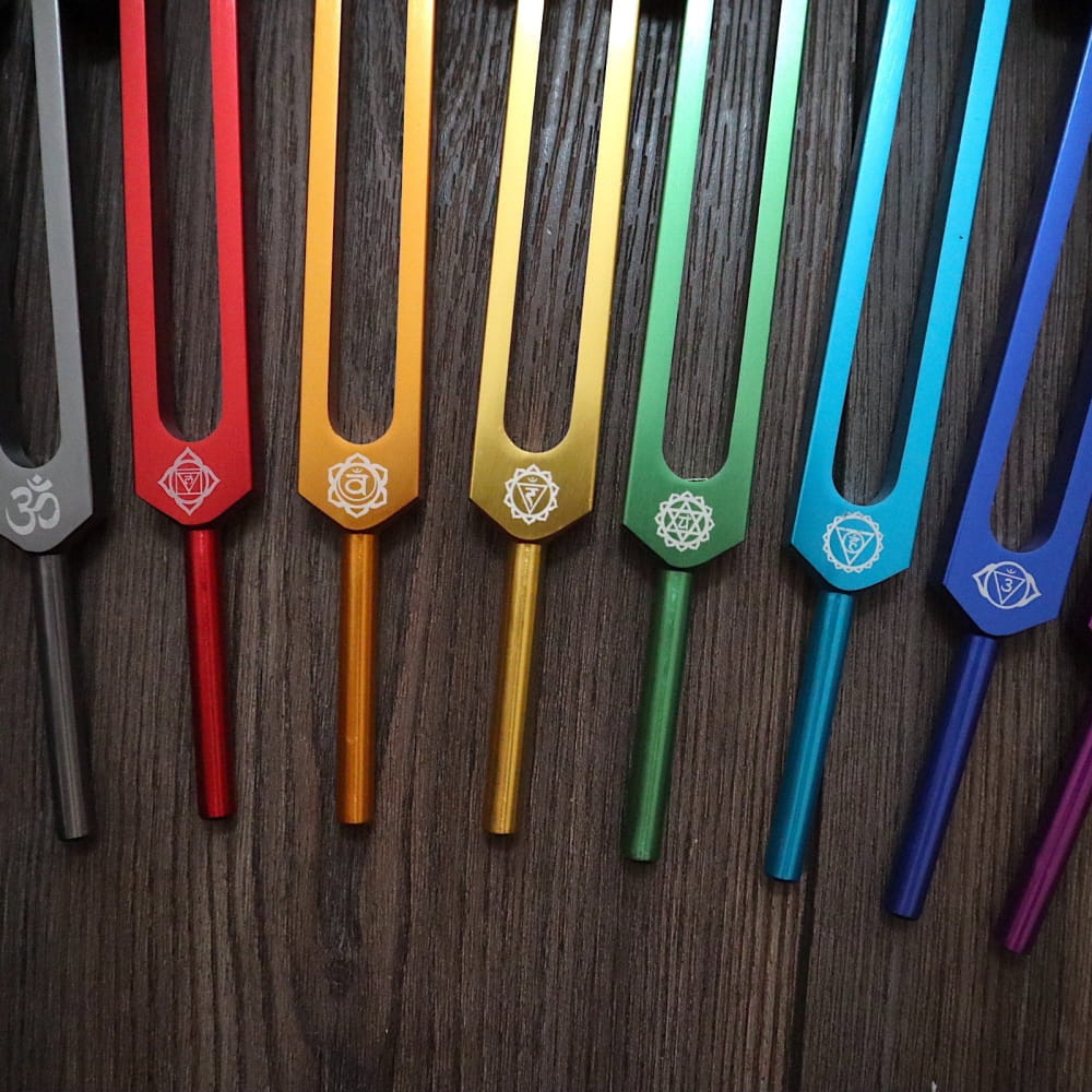 Colorful tuning forks in rainbow pattern with chakra symbols for biofield healing