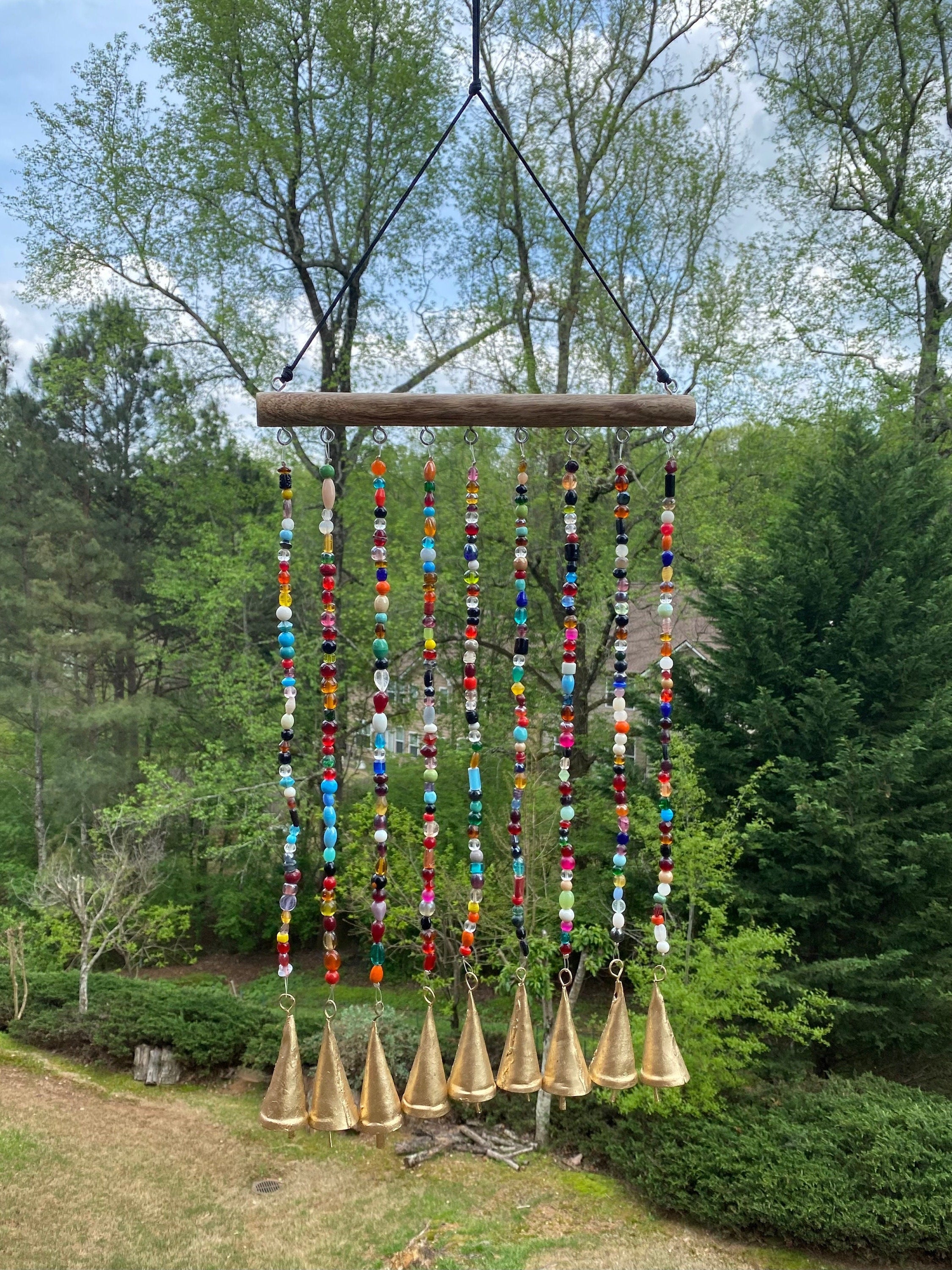 Colorful beaded wind chime with multiple strands hanging from a wooden branch