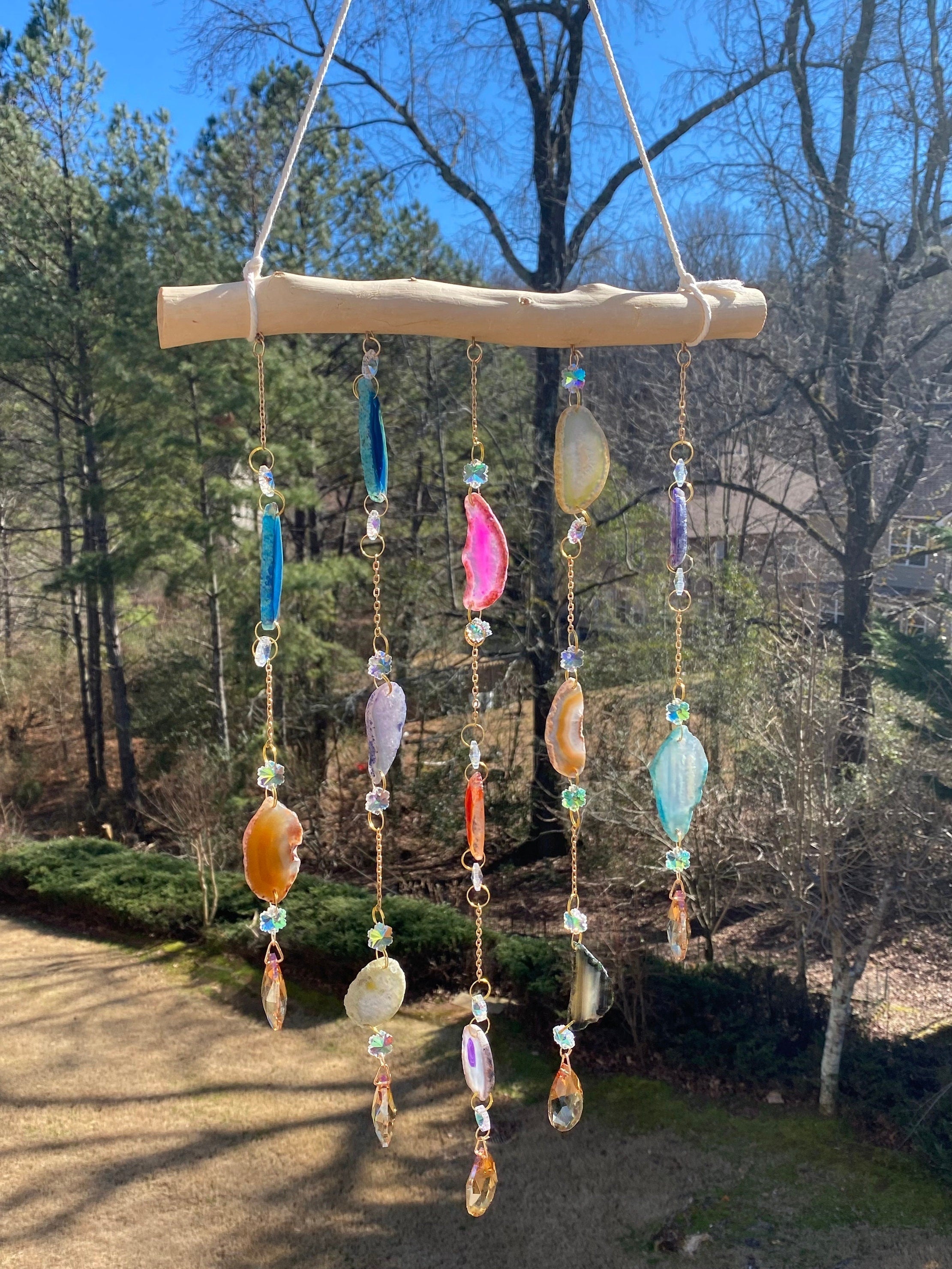 Decorative wind chime with colorful seashells and beads hanging from wooden crossbar