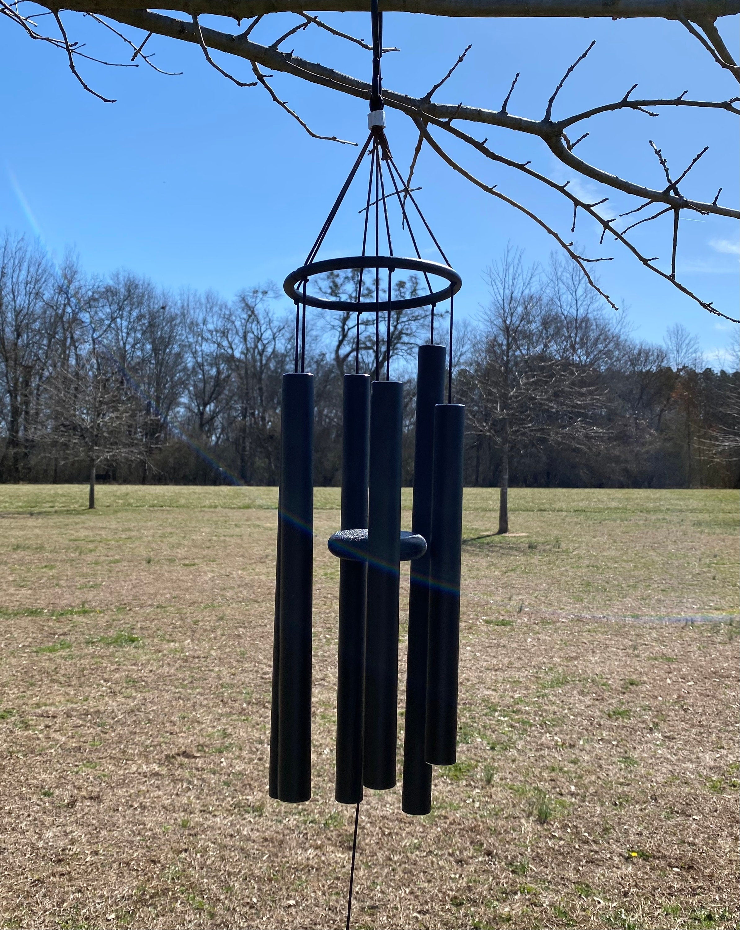 Black metal wind chimes hanging from a tree branch, 36-inch deep tone design