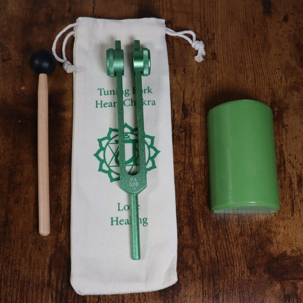 Green metallic 528 Hz tuning fork with heart chakra symbol in white pouch for healing