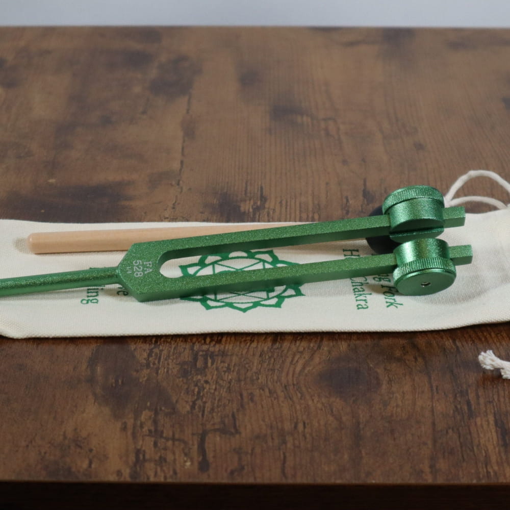 Green metal Kendama toy with white base for healing therapy and chakra alignment