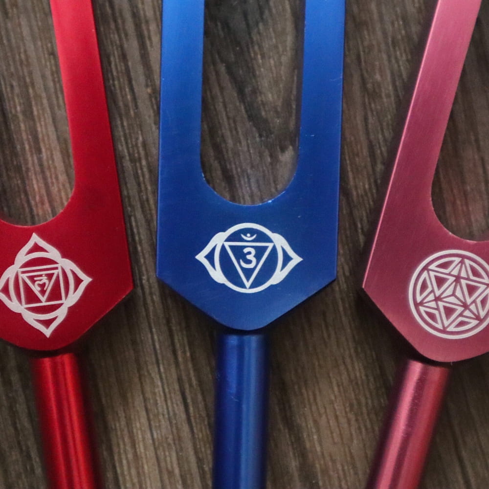Three colored tuning forks with mystical symbols for Chakra healing and music therapy