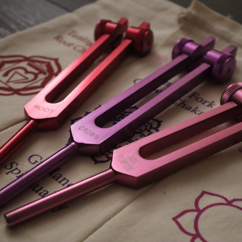 Three colorful tuning forks in red, purple, and pink for chakra healing set