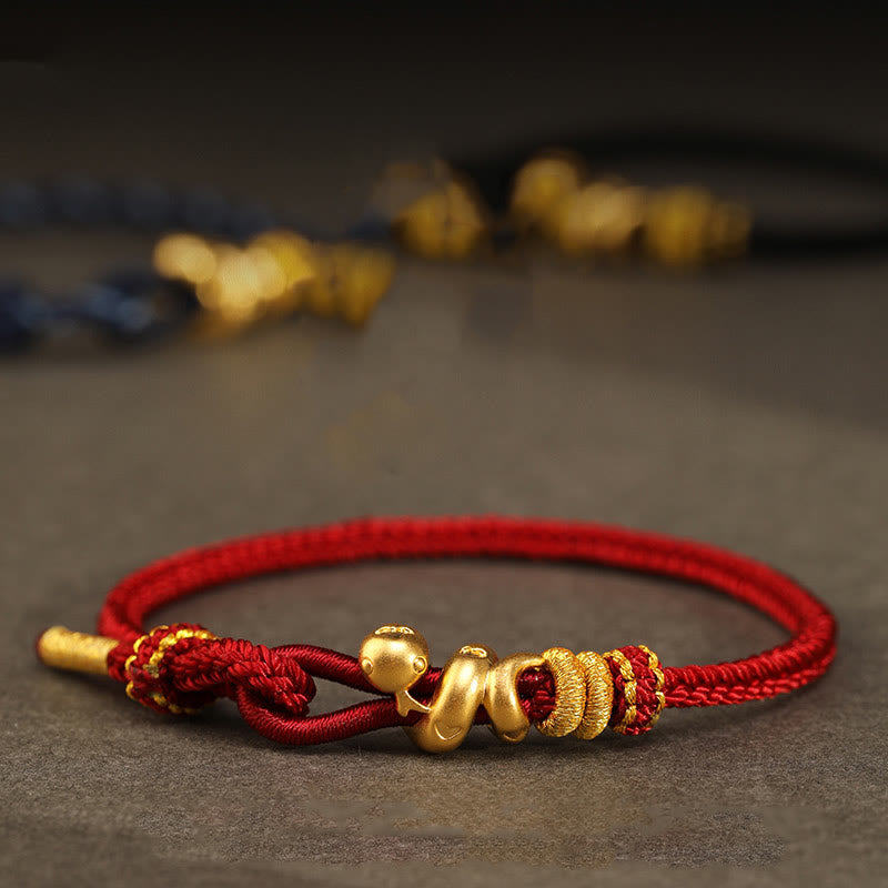 Goldfarbenes Schlangenarmband mit roter Schnur für Stärke und Schutz