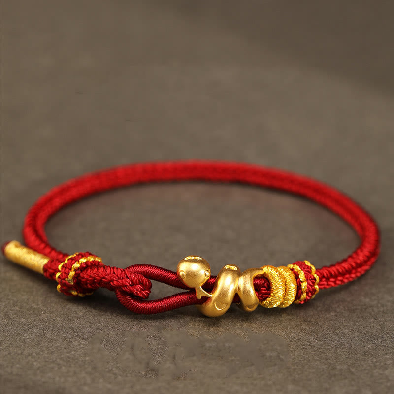 Goldfarbenes Schlangenarmband mit roter Schnur für Stärke und Schutz