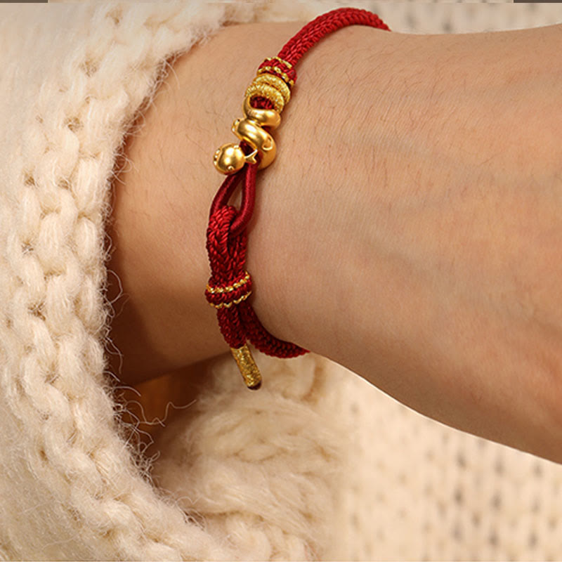 Goldfarbenes Schlangenarmband mit roter Schnur für Stärke und Schutz
