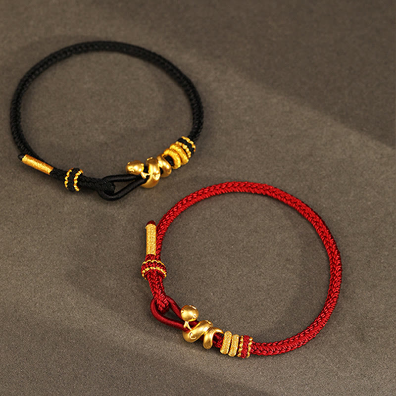 Goldfarbenes Schlangenarmband mit roter Schnur für Stärke und Schutz