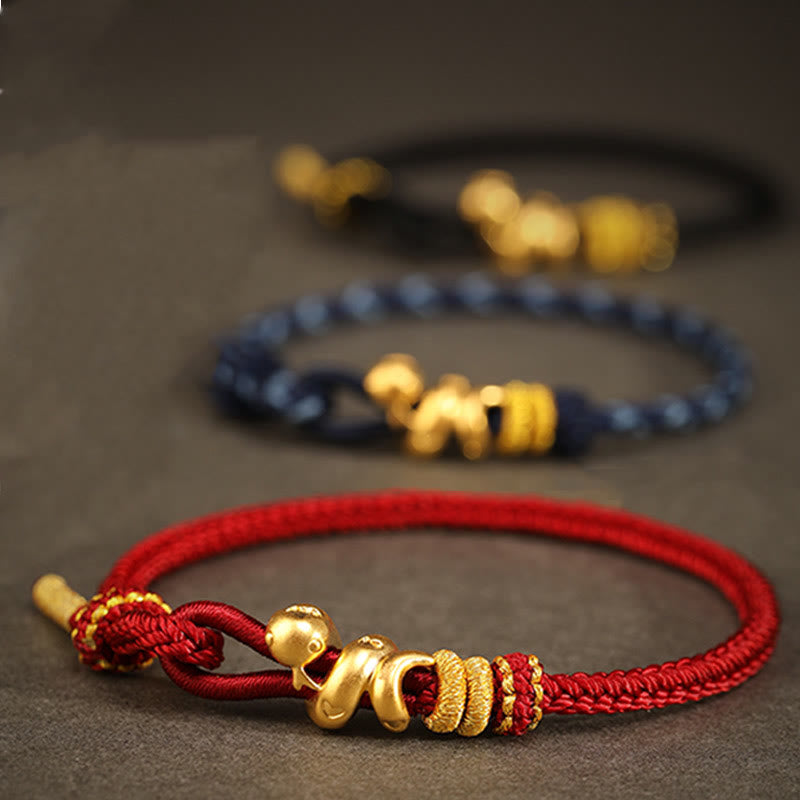 Goldfarbenes Schlangenarmband mit roter Schnur für Stärke und Schutz