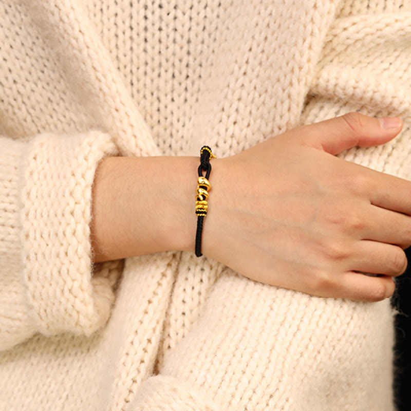 Goldfarbenes Schlangenarmband mit roter Schnur für Stärke und Schutz