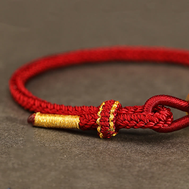 Goldfarbenes Schlangenarmband mit roter Schnur für Stärke und Schutz