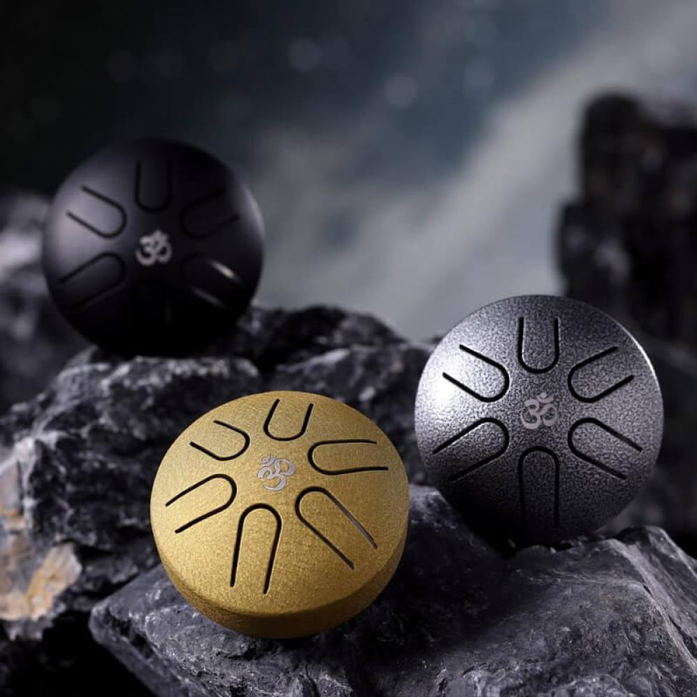 Three Mini Titanium Steel Tongue Drums in gold, silver, and black finishes with Om symbols