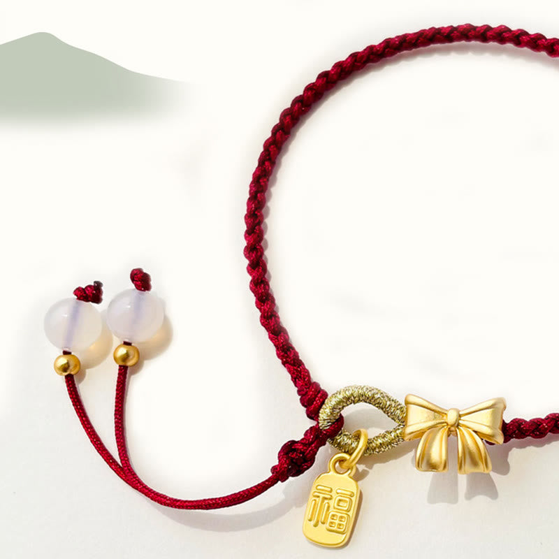 Rotes Schnurarmband mit Fu-Charm-Anhänger und Pfirsichblüten-Detail