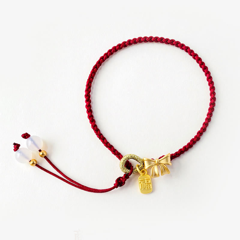 Rotes Schnurarmband mit Fu-Charm-Anhänger und Pfirsichblüten-Detail