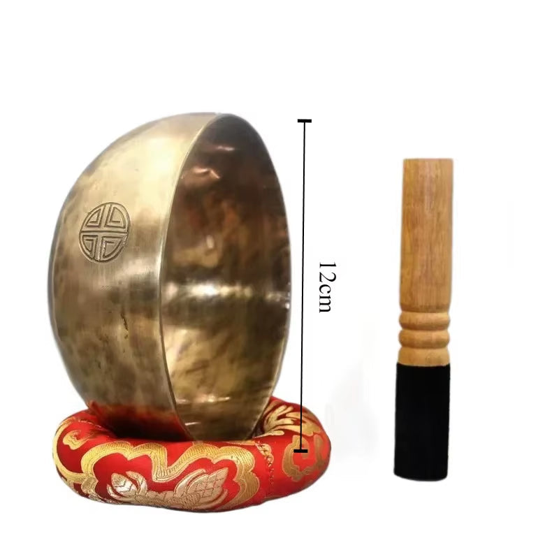 Tibetan Singing Bowl on red cushion with wooden striker for meditation and healing