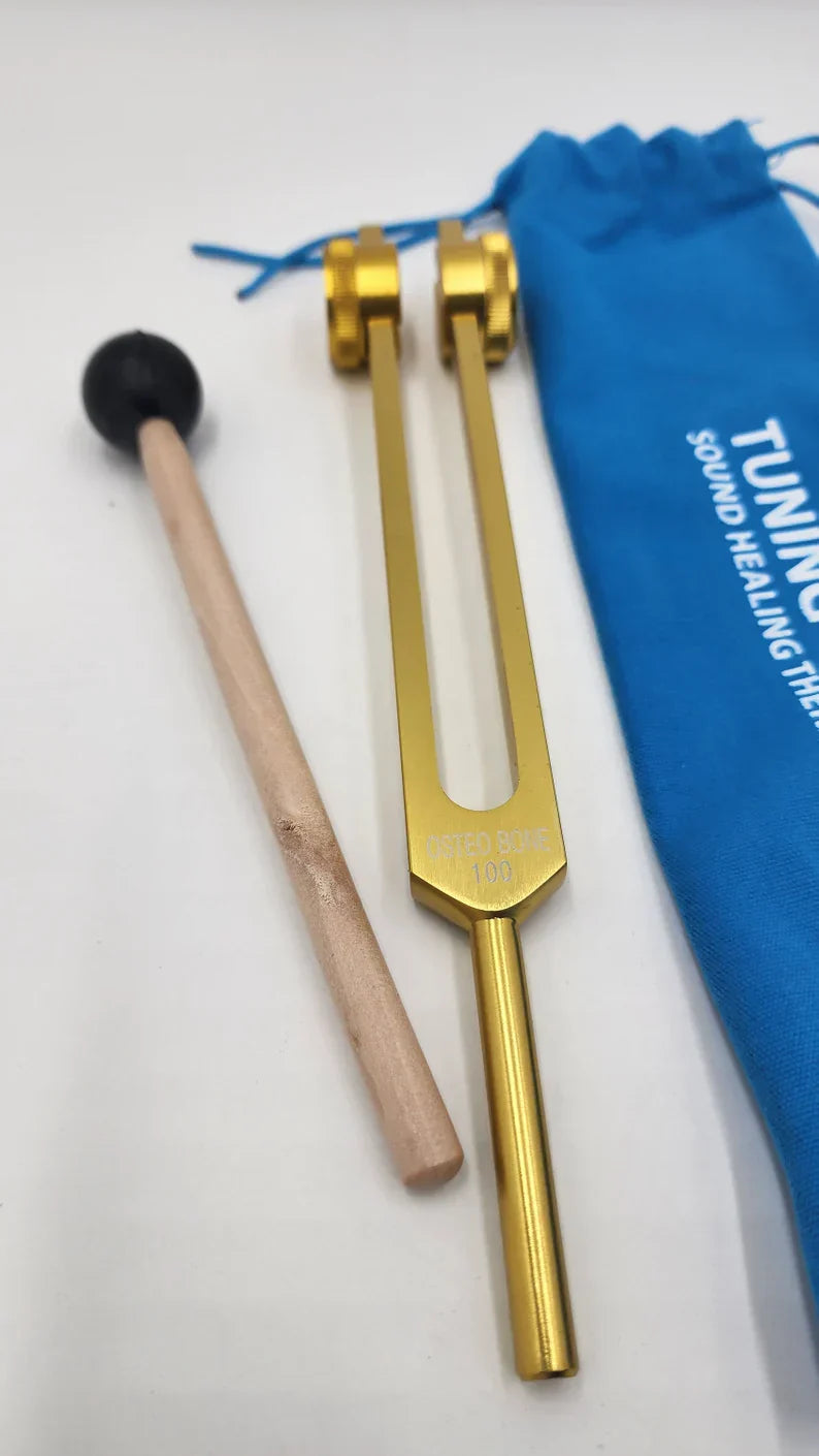 Golden tuning fork with wooden mallet and blue pouch for healing therapy