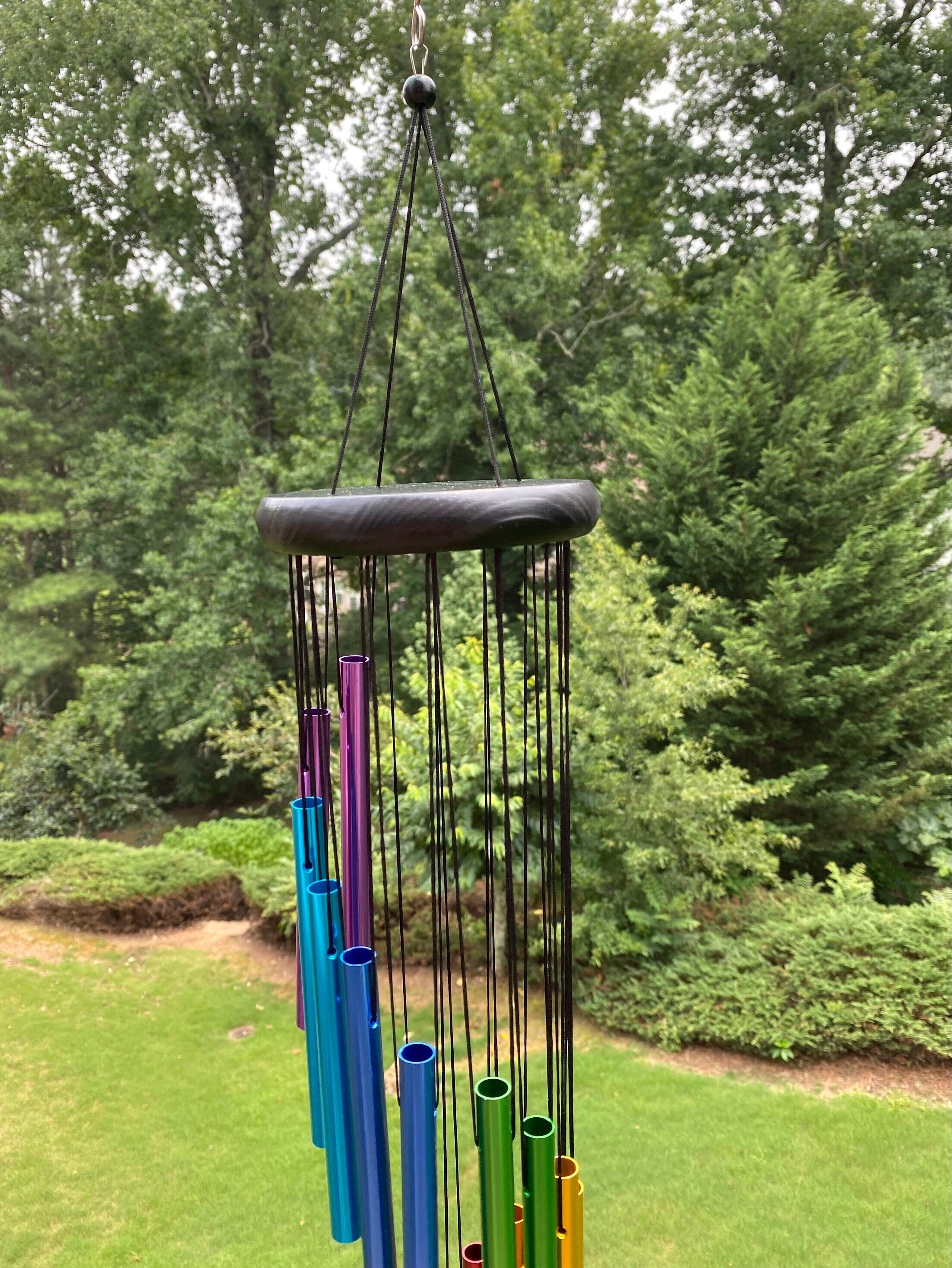 Rainbow-colored wind chimes with metal tubes hanging from a circular frame for outdoors