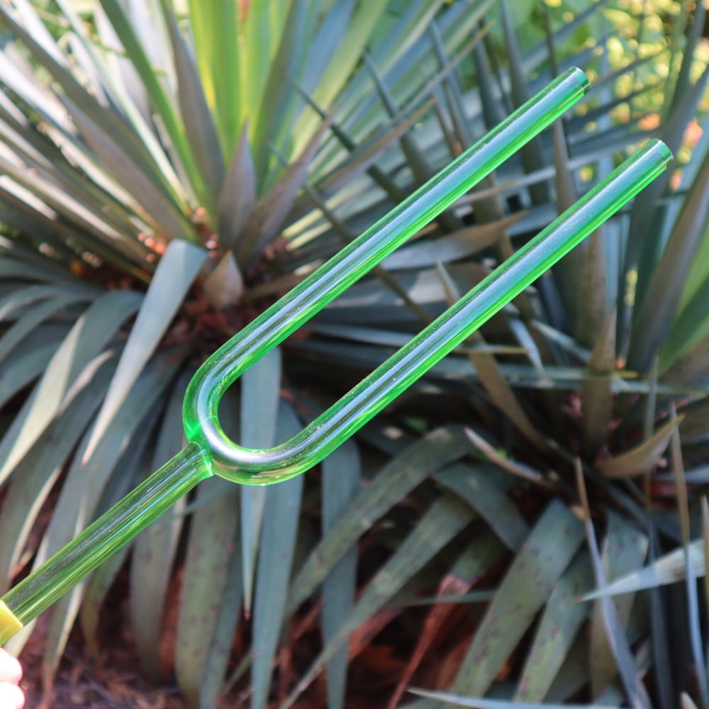 Green plastic drinking straw bent in U-shape next to 432 Hz Giant Large Crystal Tuning Fork