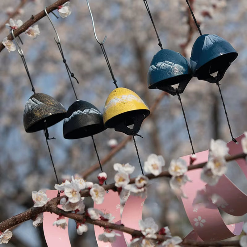 Colorful bicycle helmets hanging on wires beside a Japanese Iron Wind Chime