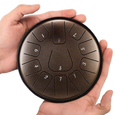 Steel tongue drum with numbered sections held in hands, 6-Inch Carbon Steel in D Key