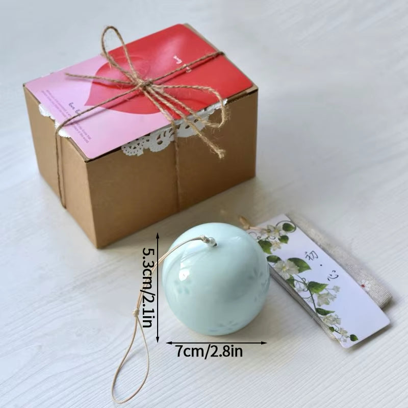 Light blue spherical bath bomb with gift tag next to Japanese Ceramic Wind Chimes