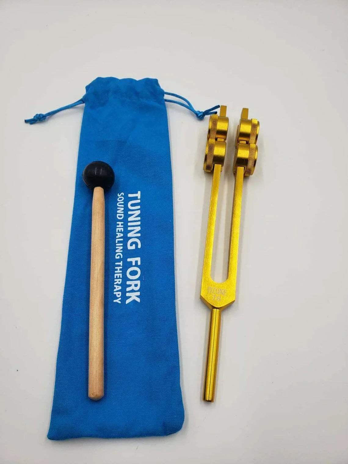 Gold 78 Hz tuning fork with wooden striker and blue storage pouch for healing