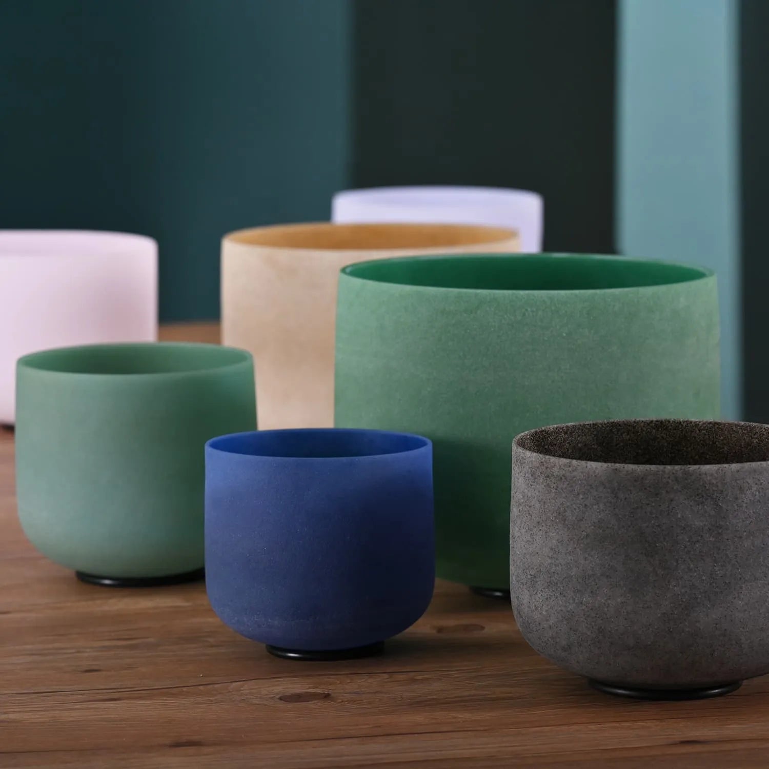 Colorful ceramic planters in a row with Gemstone Crystal Singing Bowl Set displayed