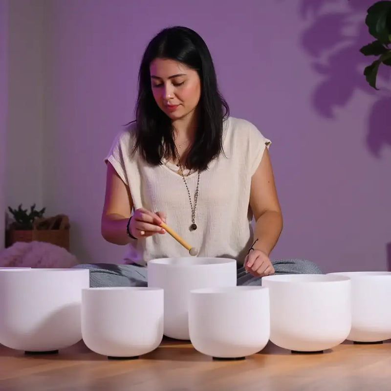 Set of white ceramic singing bowls arranged on a wooden surface.
