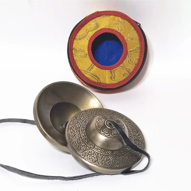 Brass Tibetan meditation tingsha cymbals with etched patterns in protective case
