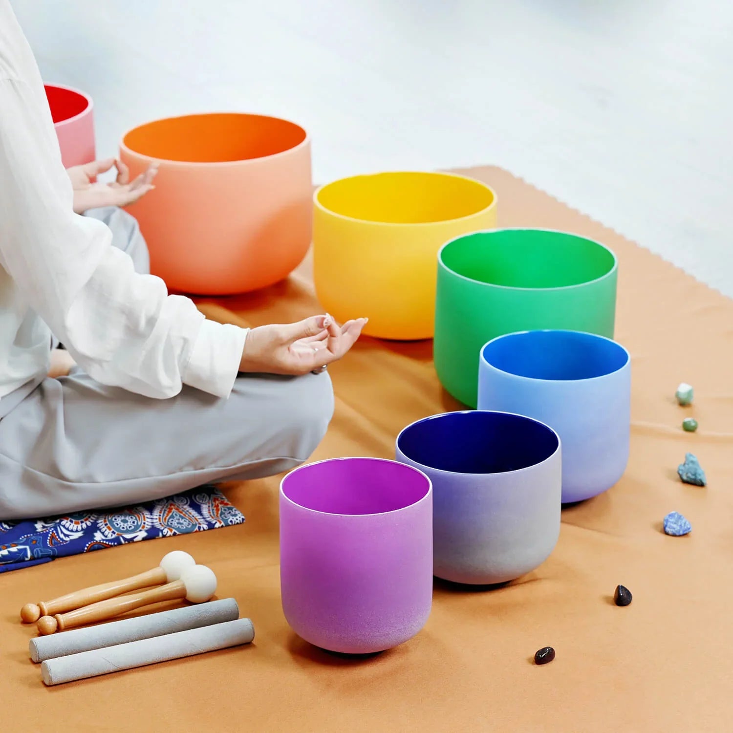 Set of rainbow-colored crystal singing bowls with mallets for chakra healing