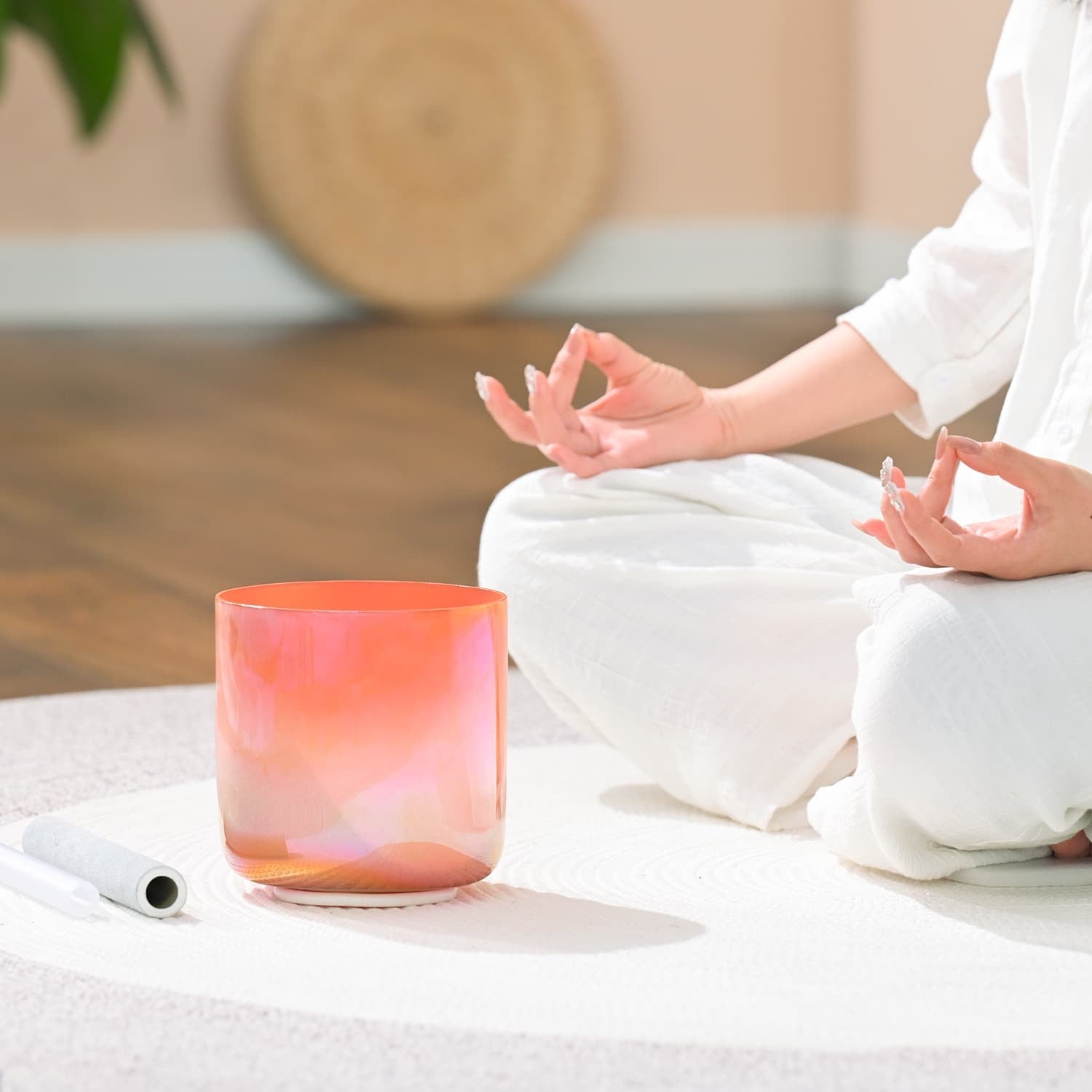 Pink glowing meditation candle next to a person in lotus pose with Crystal Singing Bowl