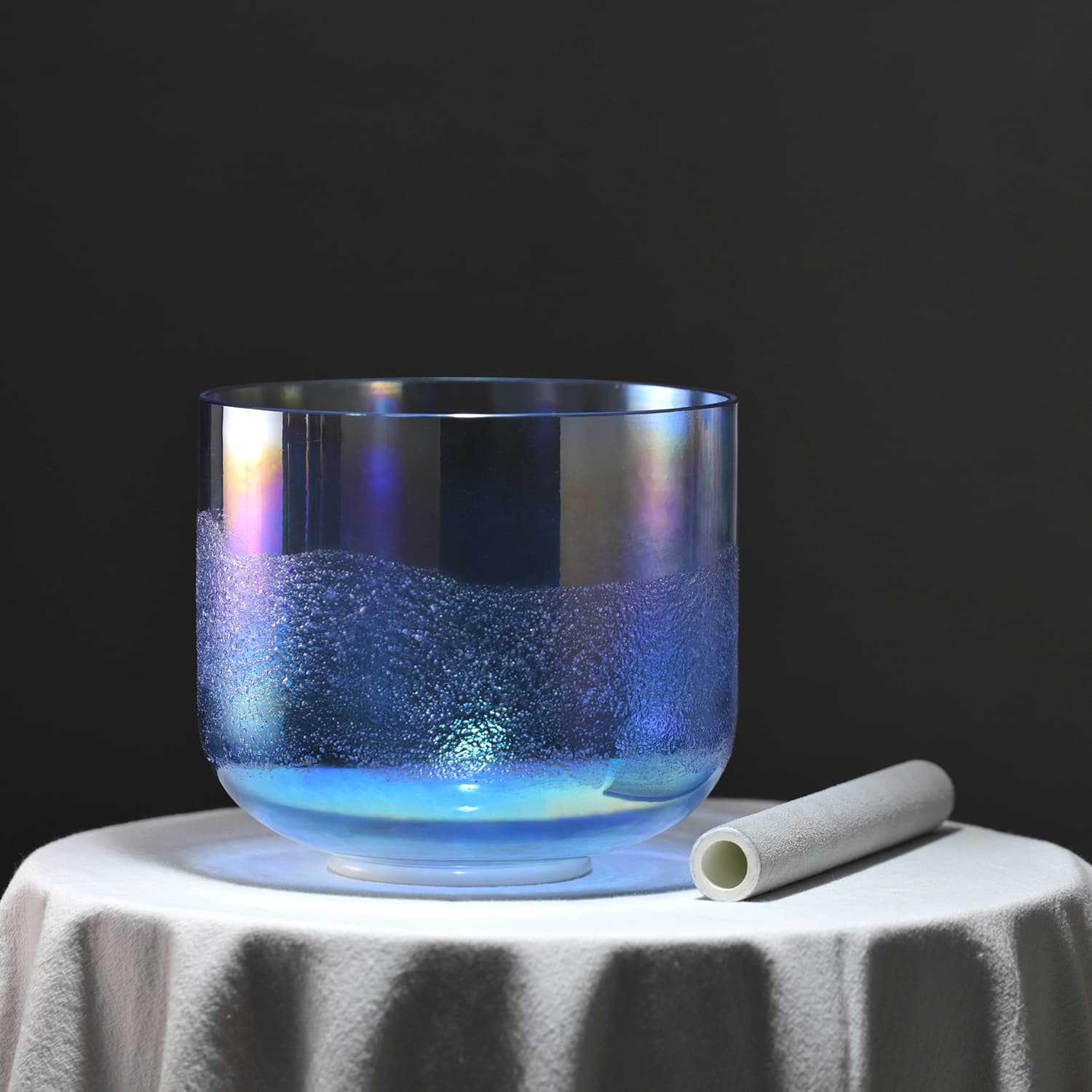 Glass tumbler with glowing blue liquid beside Crystal Singing Bowl Glacier Sand