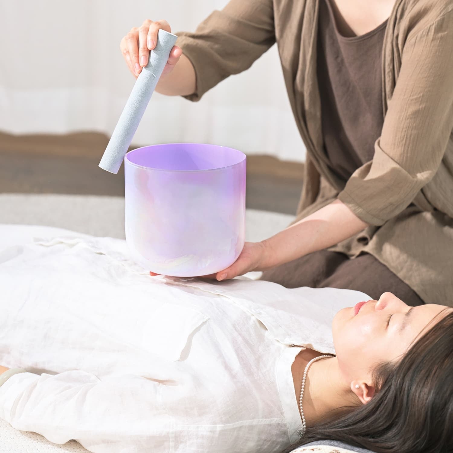 Cylindrical frosted crystal singing bowl with purple glow for sound healing