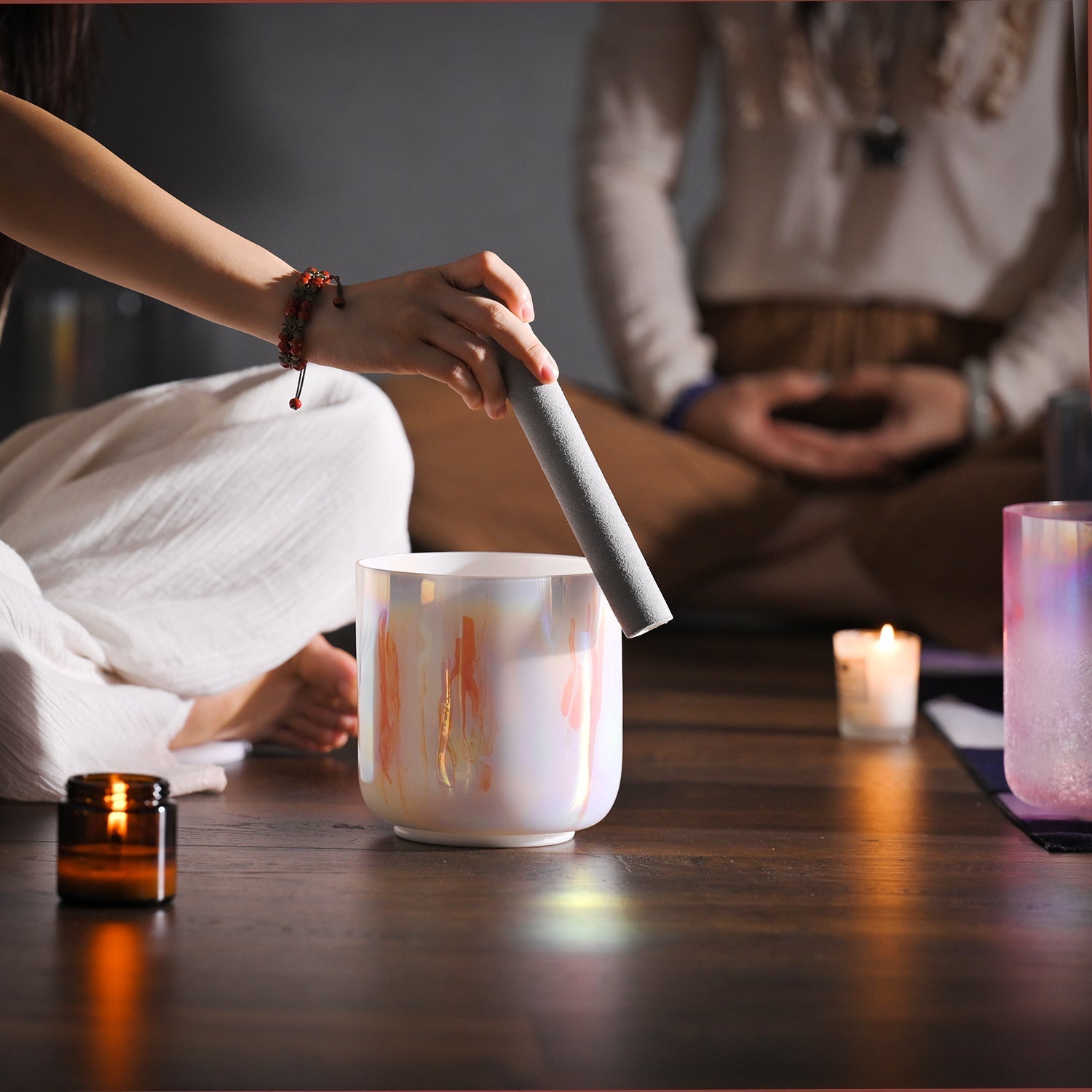 White ceramic container with orange streaks filled by a handheld device for sound healing