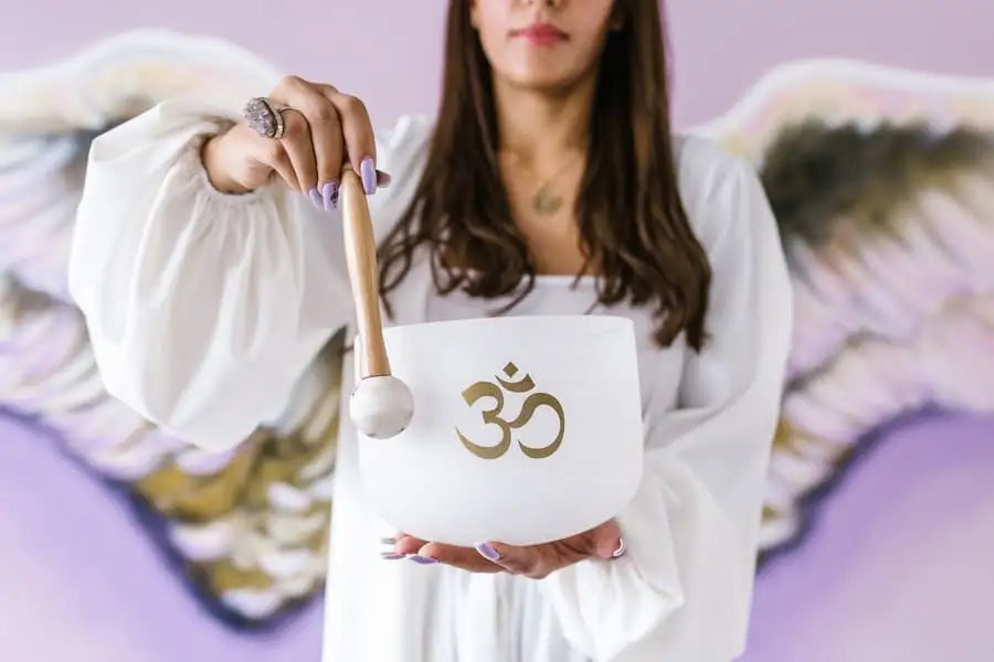 White ceramic singing bowl with gold om symbol and wooden mallet