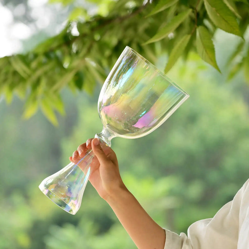 A clear, iridescent glass wine goblet with a slender stem and flared bowl.