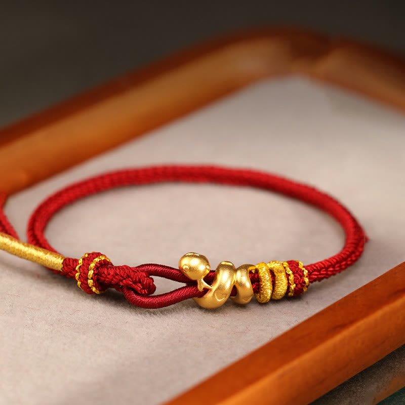 Goldfarbenes Schlangenarmband mit roter Schnur für Stärke und Schutz