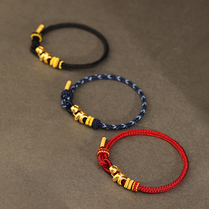Goldfarbenes Schlangenarmband mit roter Schnur für Stärke und Schutz