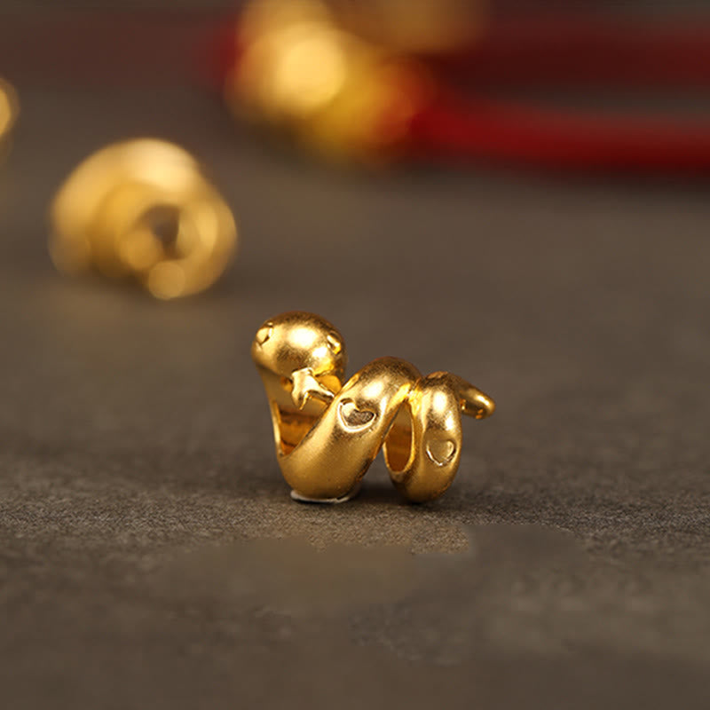 Goldfarbenes Schlangenarmband mit roter Schnur für Stärke und Schutz