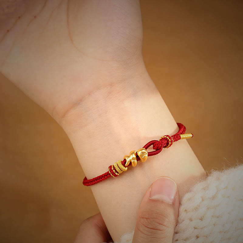 Goldfarbenes Schlangenarmband mit roter Schnur für Stärke und Schutz