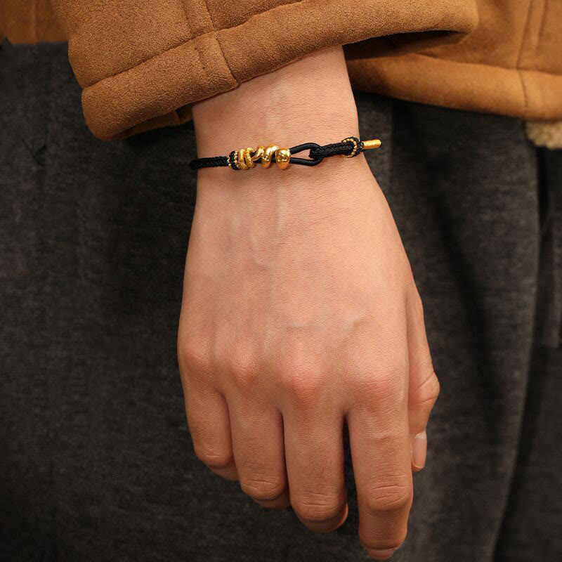 Goldfarbenes Schlangenarmband mit roter Schnur für Stärke und Schutz