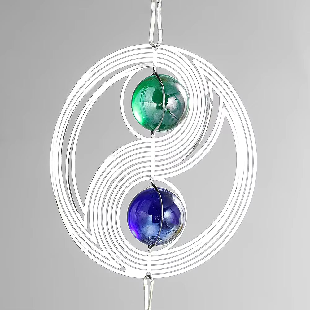 White spiral wire design with green and blue marbles in yin-yang pattern for garden decor