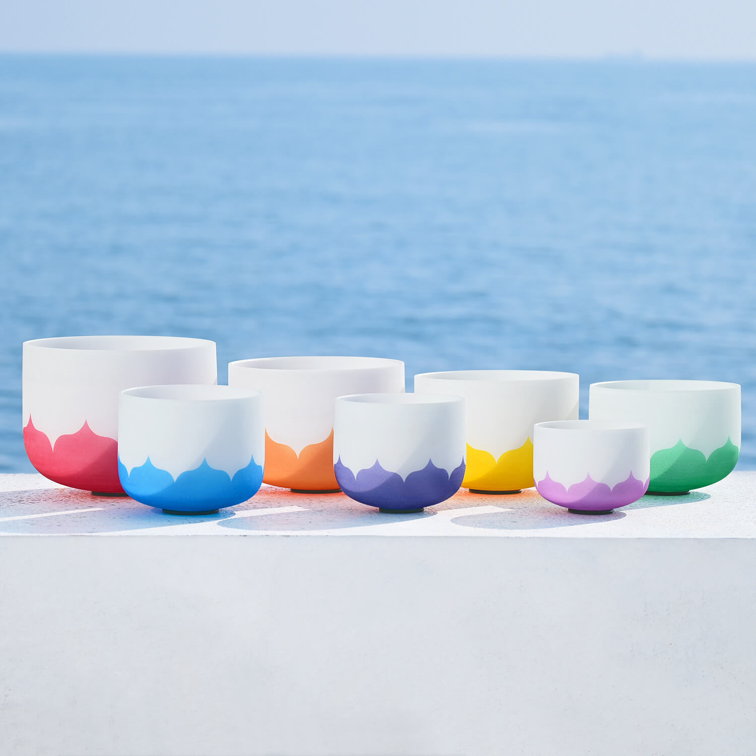 Colorful ceramic bowls with white tops in the Lotus Frosted Quartz Crystal Singing Bowl Set