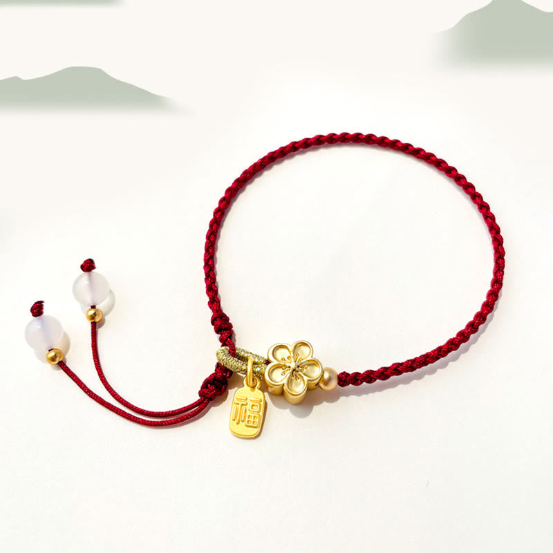 Rotes Schnurarmband mit Fu-Charm-Anhänger und Pfirsichblüten-Detail