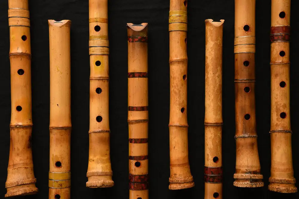 A collection of natural bamboo flutes, each with distinct finger holes and subtle decorative bands in earthy tones.