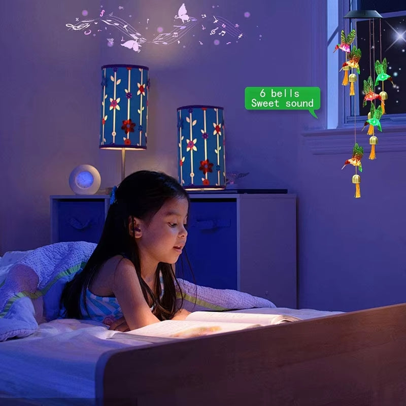 Child reading in bed under blue lanterns and fairy lights with garden decor